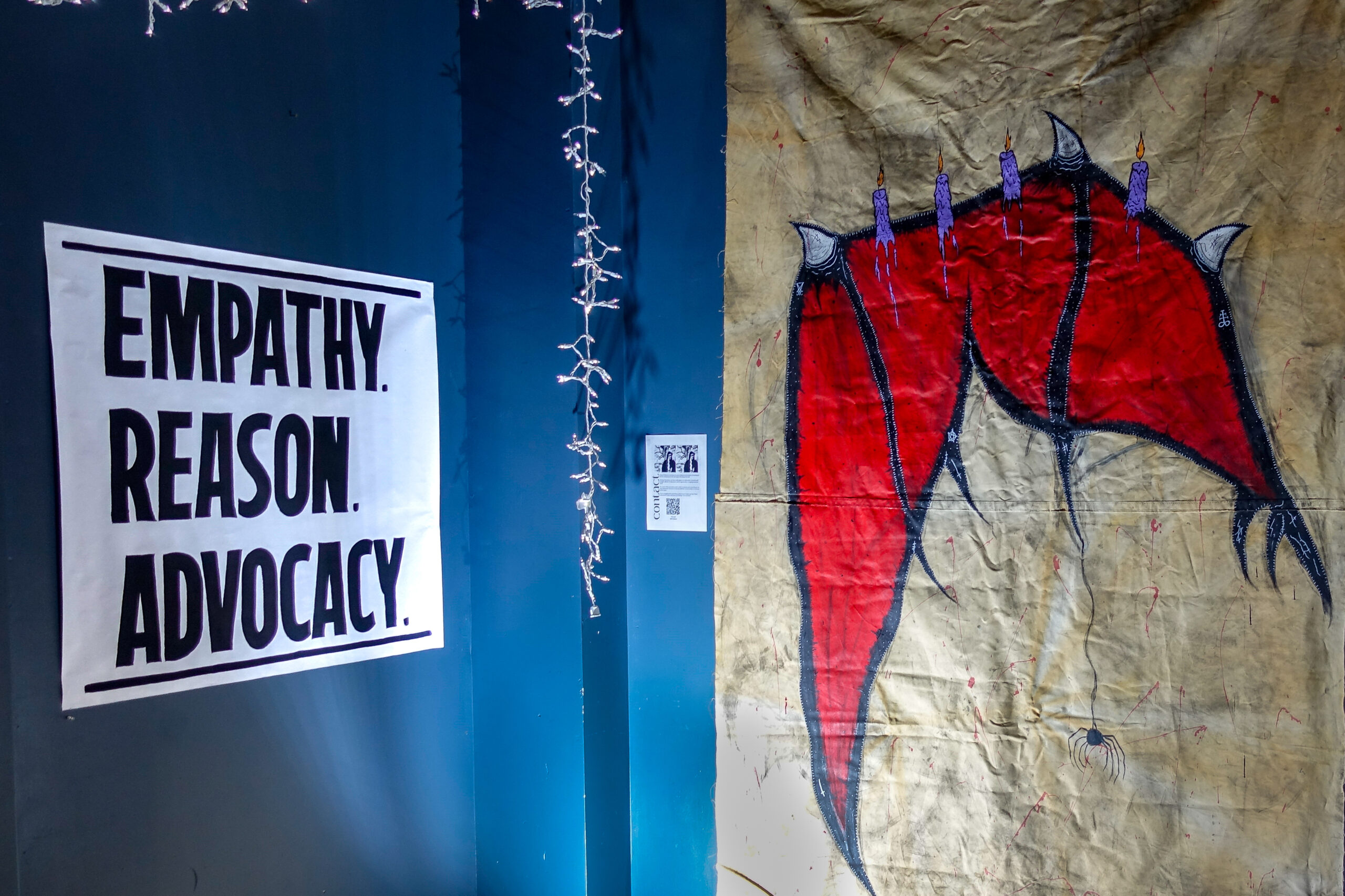 A sign reading "Empathy. Reason. Advocacy." on display next to a devil's wing at TST's Satanic Revival event.